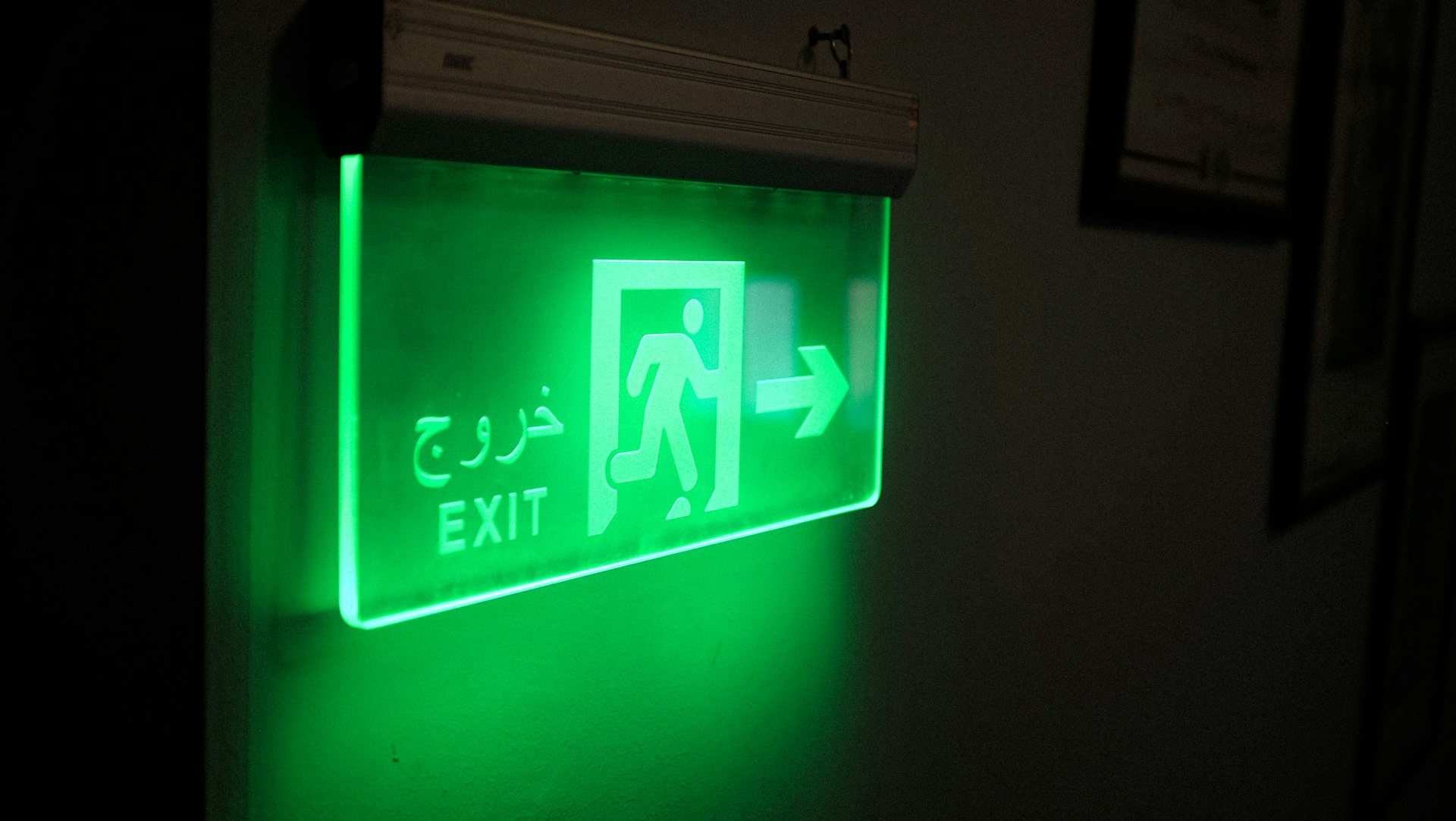 a green exit sign lit up in the dark